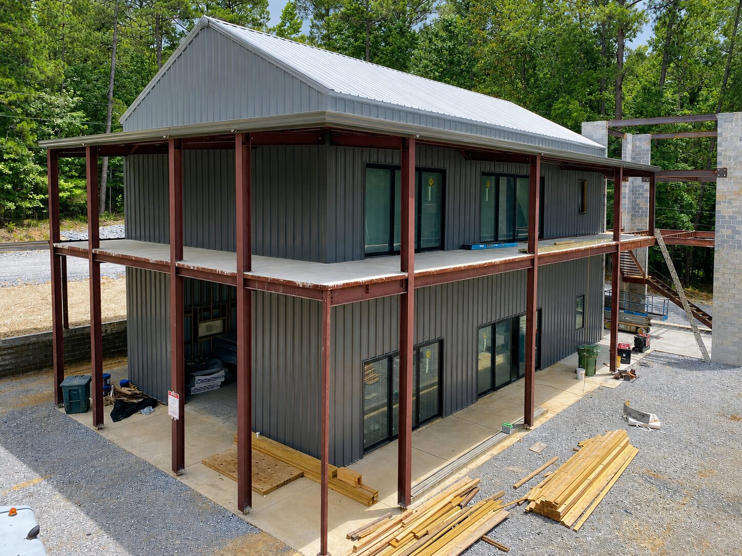 Two-story pre-engineered barndominium with charcoal walls, Galvalume roof and red iron frame porch